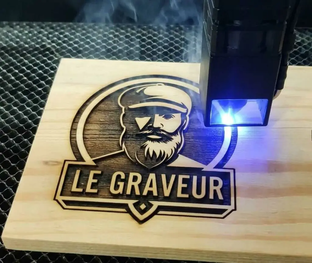 Gravure laser du logo Le Graveur sur bois clair par un laser diode bleu, illustration de l'artisanat de gravure personnalisée en France.